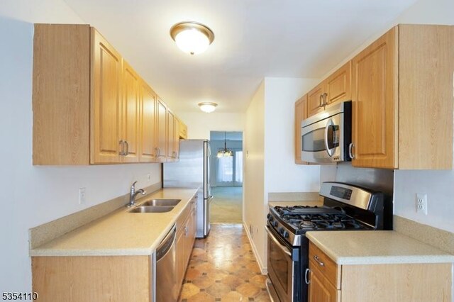 kitchen with light countertops, a sink, light brown cabinetry, and stainless steel appliances