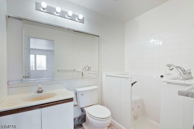 full bathroom featuring vanity, a washtub, and toilet