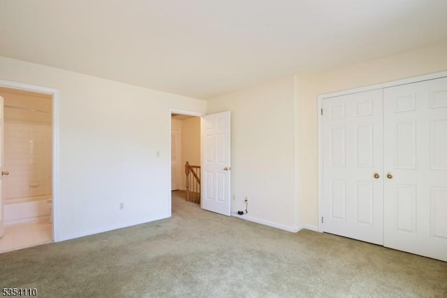 unfurnished bedroom featuring baseboards, carpet, ensuite bath, and a closet