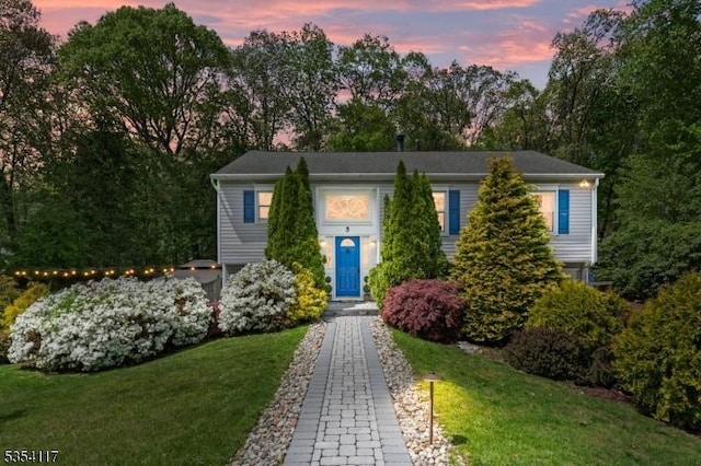 split foyer home with a lawn and view of scattered trees