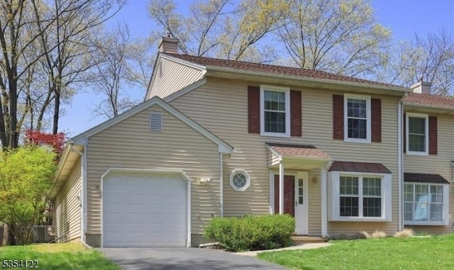 view of front of property with an attached garage, central AC unit, driveway, and a chimney