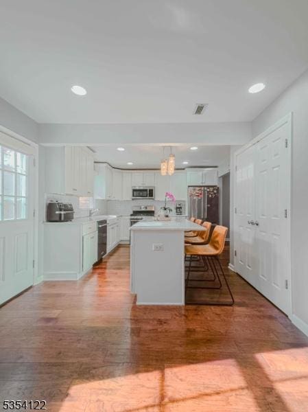 kitchen featuring appliances with stainless steel finishes, light wood finished floors, light countertops, a breakfast bar area, and white cabinetry
