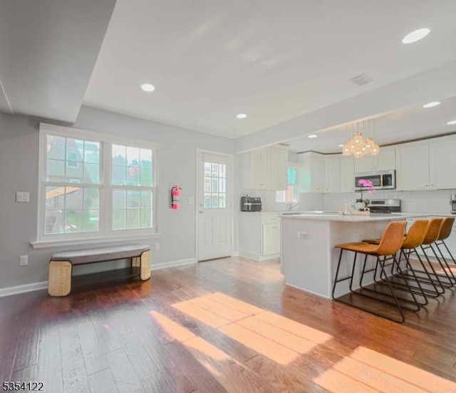 kitchen featuring white cabinets, baseboards, appliances with stainless steel finishes, and light wood-style floors