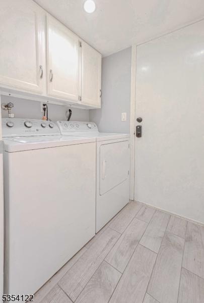 washroom featuring wood finish floors, cabinet space, and washer and clothes dryer
