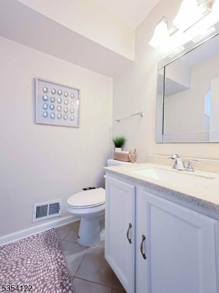 bathroom featuring tile patterned floors, vanity, toilet, and visible vents