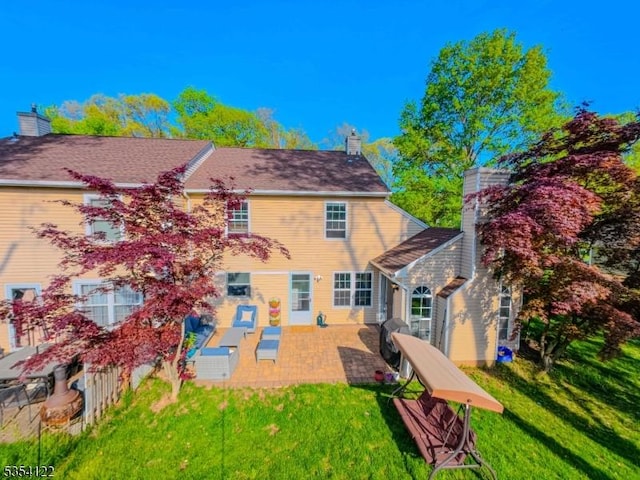rear view of house featuring a lawn, a patio, and a chimney