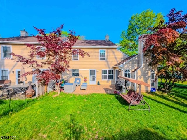 back of house with a lawn, a patio, and a chimney
