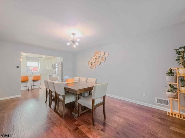 dining space with baseboards, wood finished floors, a chandelier, and visible vents