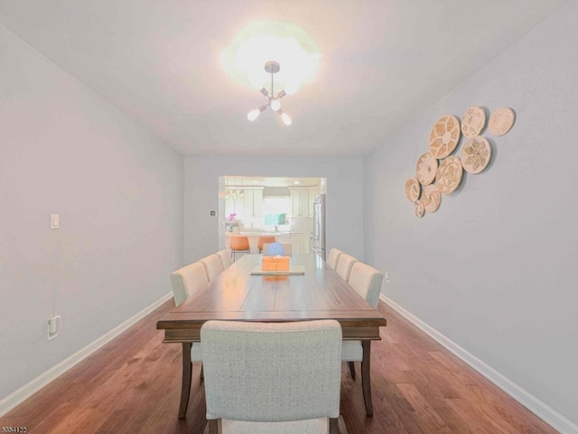 dining room with baseboards, a notable chandelier, and wood finished floors