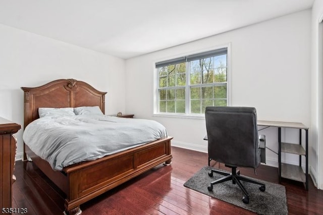 bedroom with baseboards and dark wood-type flooring