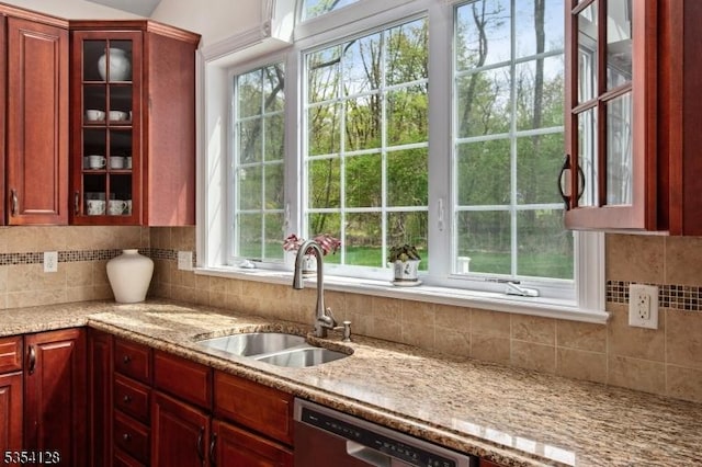 kitchen featuring a sink, glass insert cabinets, decorative backsplash, and dishwasher