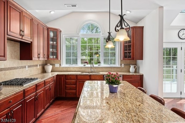 kitchen featuring light stone countertops, a sink, stainless steel gas cooktop, lofted ceiling, and visible vents
