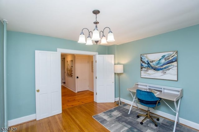 office area featuring baseboards, an inviting chandelier, and wood finished floors