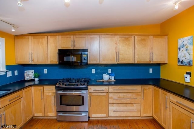 kitchen featuring black microwave, dark countertops, gas range, rail lighting, and backsplash