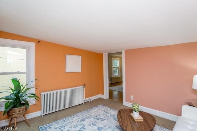 living area with baseboards, carpet, and radiator