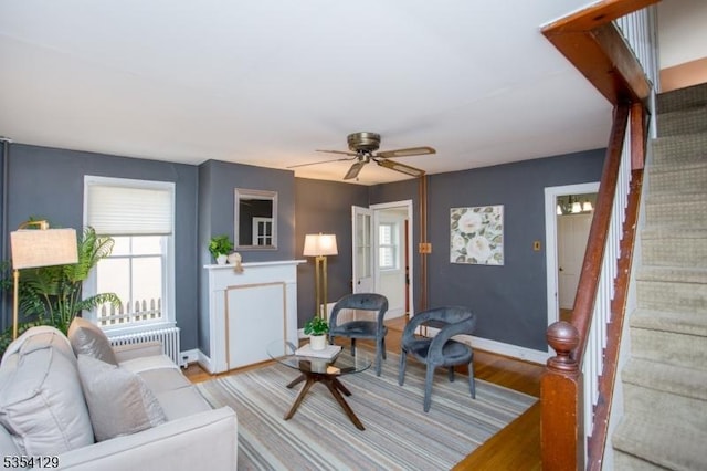 living area featuring stairs, a healthy amount of sunlight, radiator heating unit, and light wood-style floors