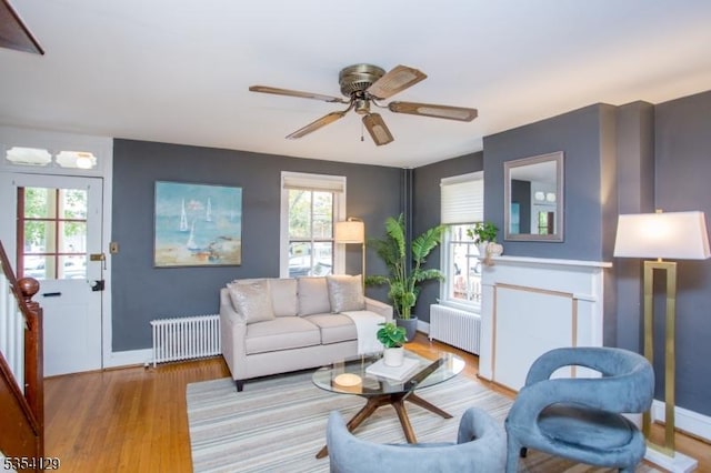 living area featuring baseboards, ceiling fan, radiator, and wood finished floors