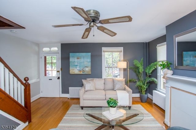 living room with light wood-type flooring, radiator heating unit, and a healthy amount of sunlight