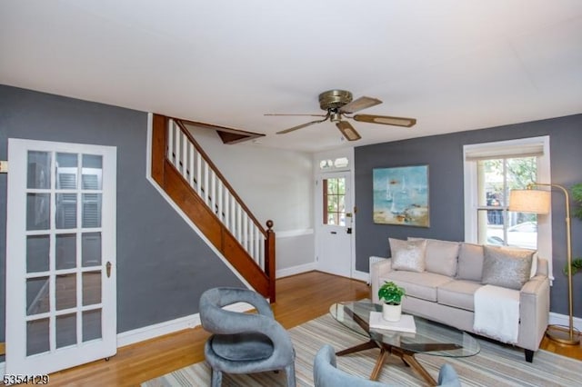living room featuring plenty of natural light, a ceiling fan, stairs, and wood finished floors