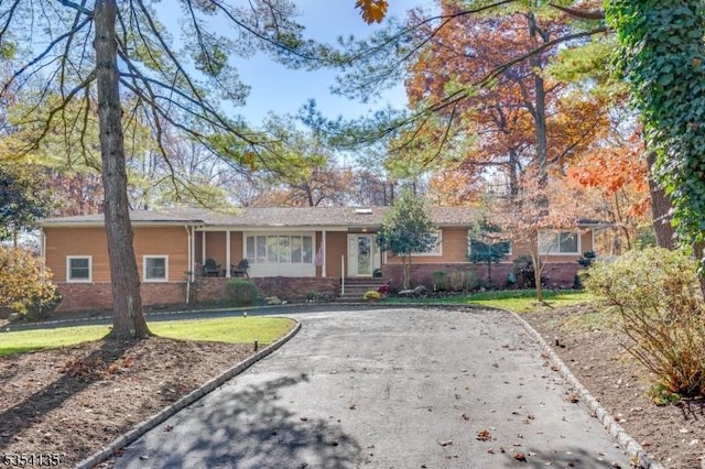 ranch-style home featuring brick siding, a front yard, and aphalt driveway