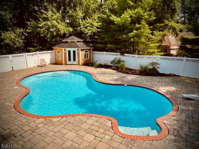 view of pool with a fenced in pool, a fenced backyard, a patio area, and an outbuilding