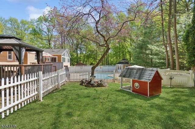 view of yard with a fenced backyard, a shed, a gazebo, a swimming pool, and an outbuilding