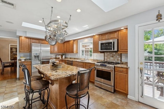 kitchen with a skylight, a kitchen island, stainless steel appliances, and a healthy amount of sunlight