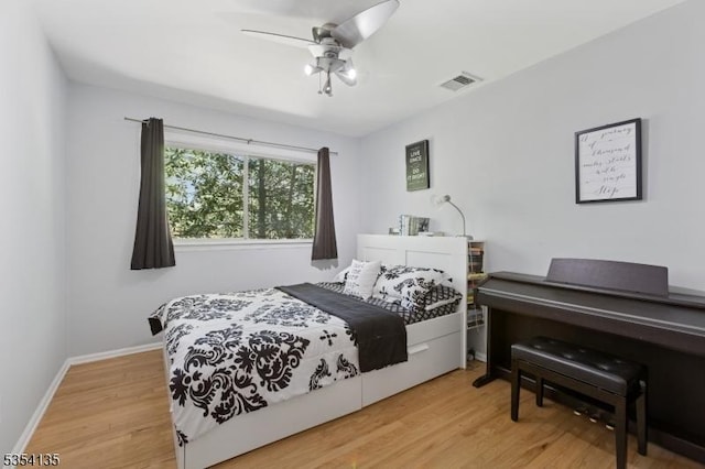 bedroom featuring a ceiling fan, baseboards, visible vents, and wood finished floors