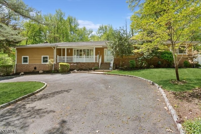 ranch-style home featuring a porch, brick siding, driveway, and a front lawn
