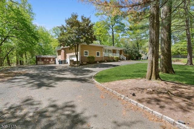 view of front facade featuring an attached garage, a front yard, and aphalt driveway