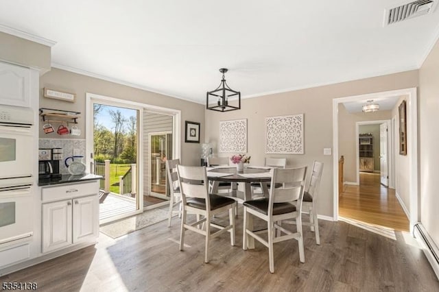 dining space with visible vents, ornamental molding, dark wood-style floors, a baseboard heating unit, and a notable chandelier
