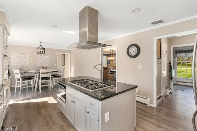 kitchen featuring island range hood, stainless steel gas stovetop, a baseboard radiator, visible vents, and dark wood-type flooring