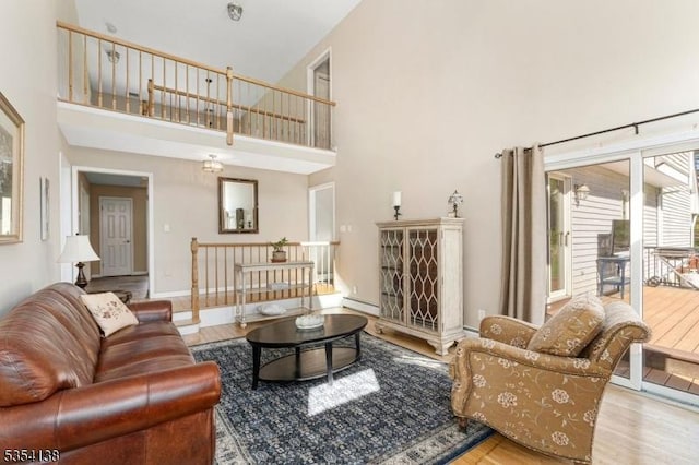 living room featuring baseboards, a high ceiling, a baseboard heating unit, and wood finished floors