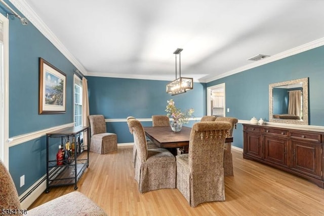 dining space with crown molding, an inviting chandelier, light wood-type flooring, and visible vents