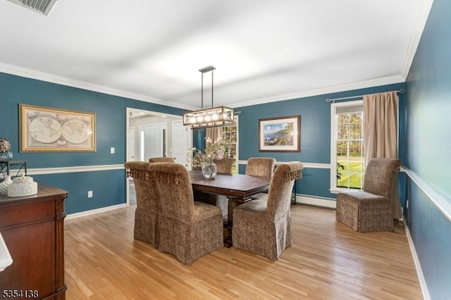 dining space featuring baseboards, light wood finished floors, crown molding, and a baseboard heating unit