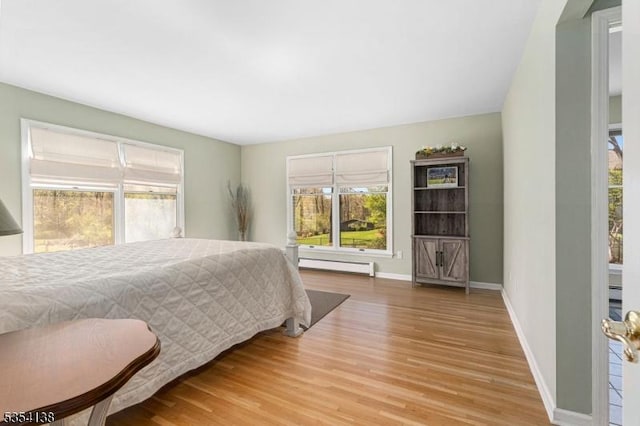bedroom with baseboards, wood finished floors, and baseboard heating