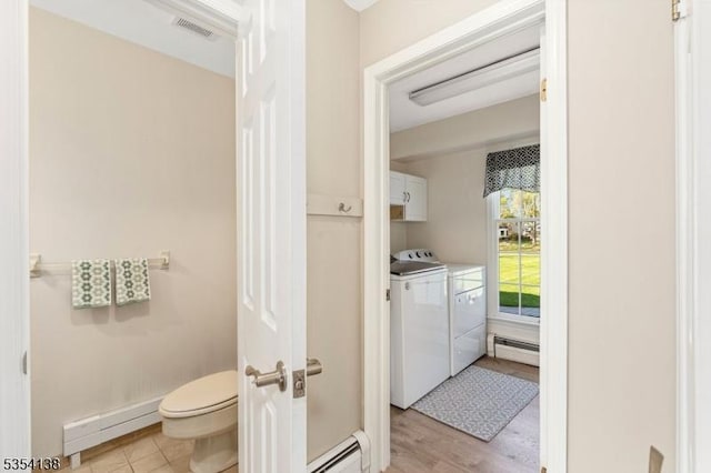 bathroom featuring independent washer and dryer, visible vents, baseboard heating, a baseboard heating unit, and toilet