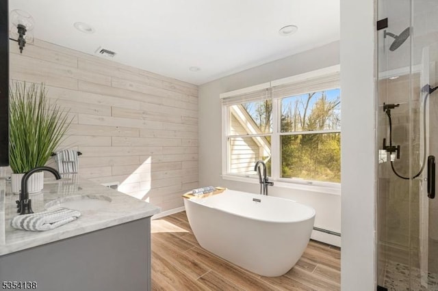 bathroom with wooden walls, vanity, a shower stall, a baseboard heating unit, and a soaking tub