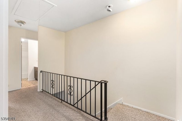hallway featuring baseboards, carpet, attic access, and an upstairs landing