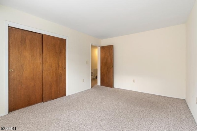 unfurnished bedroom with carpet floors, radiator heating unit, and a closet