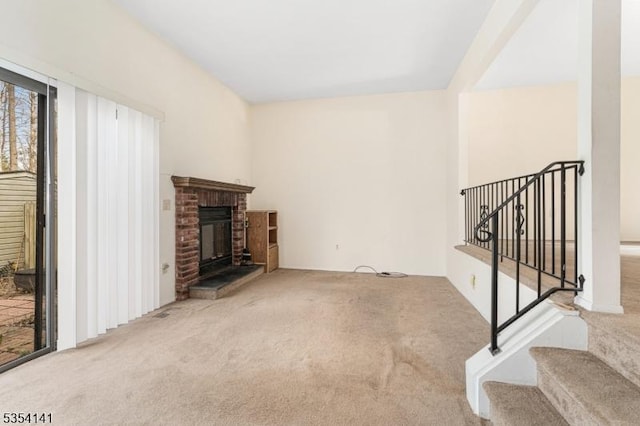 unfurnished living room featuring stairway, a fireplace, and carpet flooring