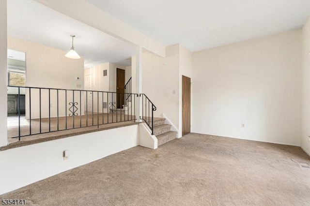 carpeted spare room featuring stairs and visible vents