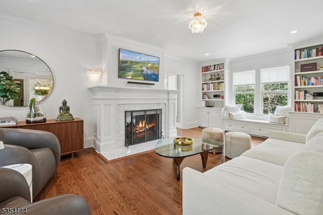 living area featuring recessed lighting, ornamental molding, light wood finished floors, and a fireplace
