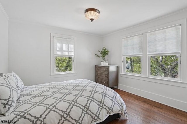 bedroom with crown molding, baseboards, multiple windows, and dark wood-type flooring