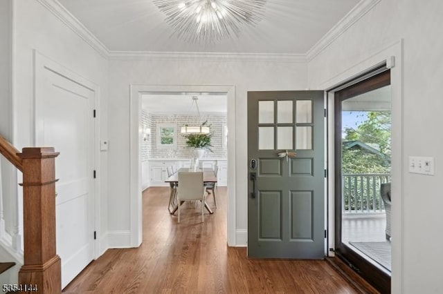 foyer entrance with crown molding, a chandelier, a healthy amount of sunlight, and wood finished floors