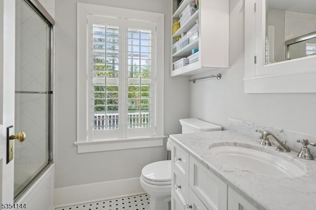 bathroom featuring bath / shower combo with glass door, plenty of natural light, vanity, and toilet