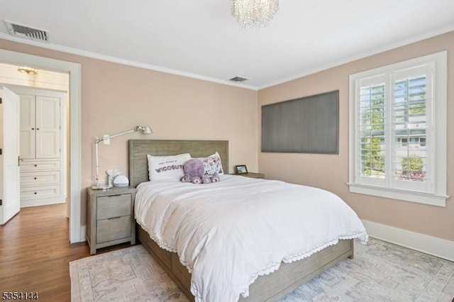 bedroom featuring crown molding, baseboards, visible vents, and wood finished floors