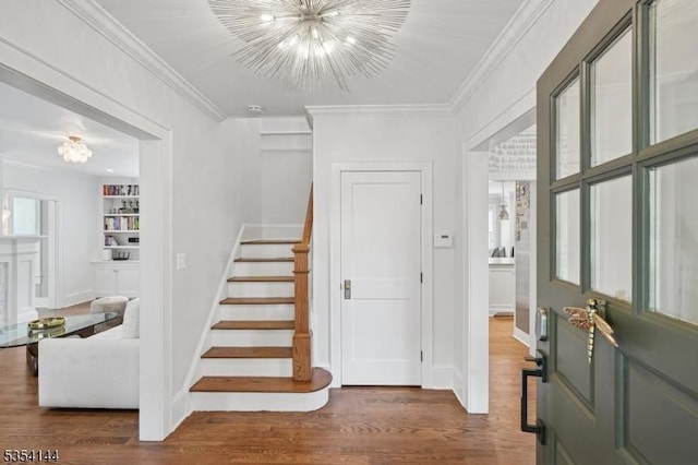 entrance foyer featuring wood finished floors, baseboards, a chandelier, ornamental molding, and stairs