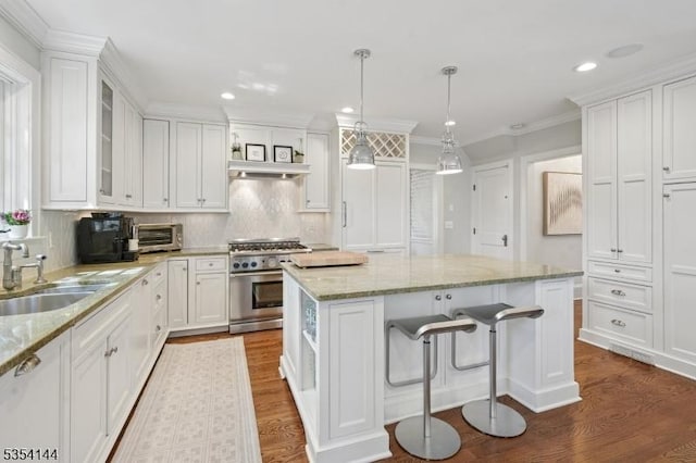 kitchen featuring a kitchen island, white cabinetry, a sink, and stainless steel stove
