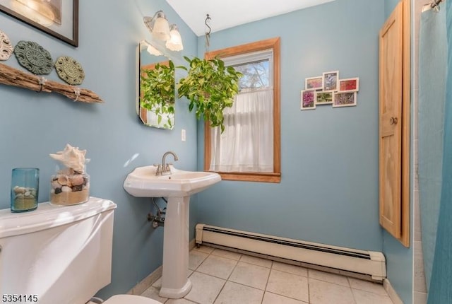 bathroom featuring toilet, tile patterned floors, a baseboard heating unit, and baseboards